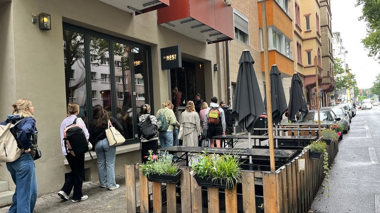 Wegen der Bombenentschärfung und Evakuierung stehen viele Leute vor einem Café in der Mainzer Neustadt Schlange.