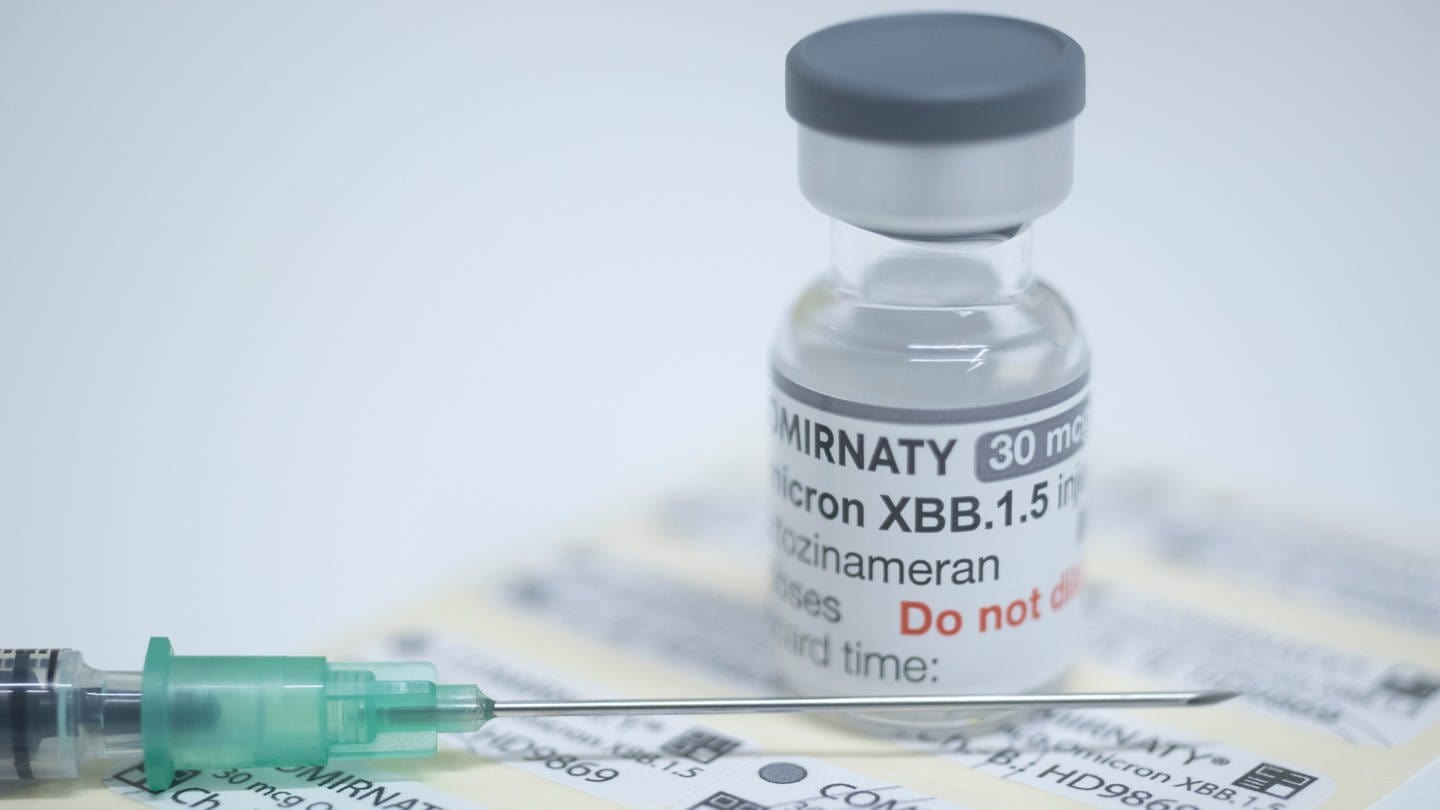 Neben einer Ampulle des Impfstoffs Comirnaty von BioNTech liegt eine Spritze.
