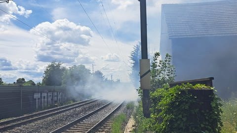 Unmittelbar neben einer Bahnstrecke im Rheingau steigt Rauch auf.