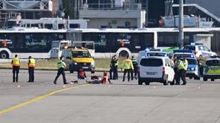 Einsatzfahrzeuge von Polizei, Feuerwehr und Flughafen-Sicherheit stehen auf dem Vorfeld des Frankfurter Flughafens, wo sich zwei Aktivisten festgeklebt haben.