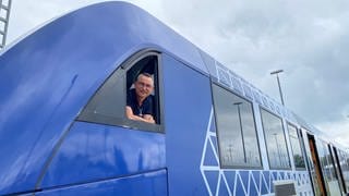 Lokführer Andreas Frank schaut aus dem Fenster seiner Fahrerkabine und lächelt  