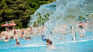 Dutzende Kinder planschen in einem Freibad.