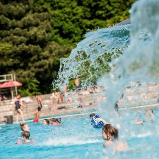 Dutzende Kinder planschen in einem Freibad.