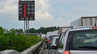 Ein Schild auf der Autobahn zeigt, wie eine Rettungsgasse richtig gebildet wird