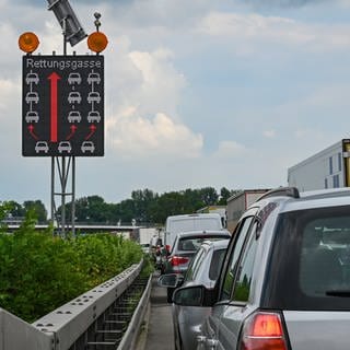 Ein Schild auf der Autobahn zeigt, wie eine Rettungsgasse richtig gebildet wird