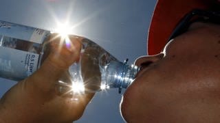 Eine Frau trinkt aus einer Flasche Wasser.