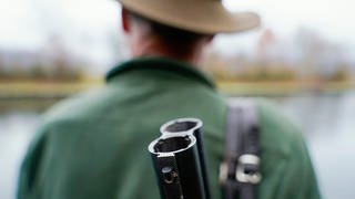 Ein Jäger trägt ein Gewehr auf dem Rücken.