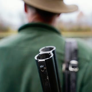 Ein Jäger trägt ein Gewehr auf dem Rücken.