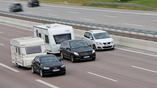 Zwei Wohnwagen-Gespanne fahren nebeneinander auf der Autobahn.