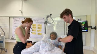 Sarah Weizel und Justin Druck üben an sprechender Patientenpuppe "Frau Vogel".