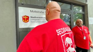 Mitarbeiter eines Sicherheitsdienstes stehen vor der Stadtverwaltung von Ludwigshafen. 