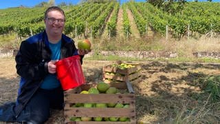 Daniel von den Lebenshilfe Werkstätten Bad Kreuznach freut sich sehr über die Äpfel, die Winzerin Ute Schweinhardt der Gruppe nach dem Apfelklau geschenkt hat.