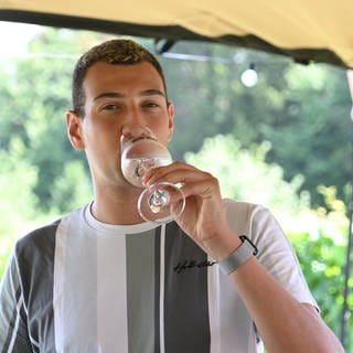 Levin McKenzie aus Wackernheim steht mit einem Gläschen Wein im Weinberg. Er ist der erste Weinkönig im Anbaugebiet Rheinhessen. 