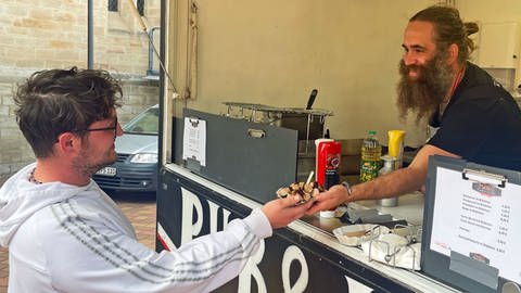 Marc Schramm steht mit seinem Foodtruck in Saulheim auf dem Wochenmarkt. Es gibt Pommes, Zwiebelkuchen, Currywurst und Rheinhessen-Döner.