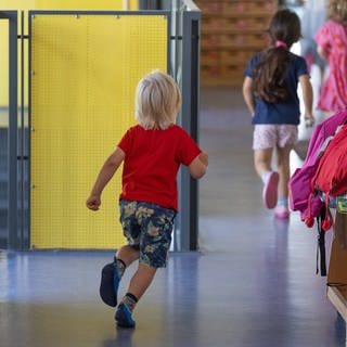 Kinder rennen über einen Flur in einer Mainzer Kita. Dort gibt es jetzt mehr Erzieherinnen und Erzieher