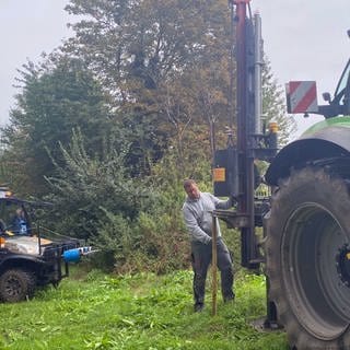 Zwei Männer errichten am Rande eines Ackers einen Zaun. In Rheinhessen werden weitere Zäune aufgestellt, um die afrikanische Scweinepest einzudämmen. 