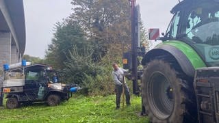 Zwei Männer errichten am Rande eines Ackers einen Zaun. In Rheinhessen werden weitere Zäune aufgestellt, um die afrikanische Scweinepest einzudämmen. 