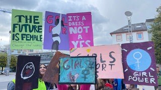 Plakate von jungen Demonstrantinnen zum Weltmädchentag