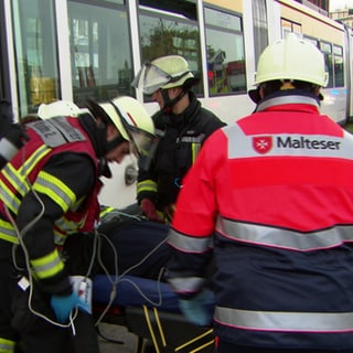 Rettungskräfte betreuen einen Mann nach einem Straßenbahnunglück in Mainz. Es handelt sich um eine nachgestellte Szene, um den Ernstfall zu proben.