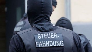 Ein vermummter Mann. Auf seinem Rücken der Schriftzug "Steuerfahndung". Bei einer Razzia wegen illegaler Prostitution wurden in Ludwigshafen und Mainz-Kostheim Verdächtige festgenommen. 