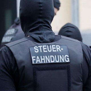 Ein vermummter Mann. Auf seinem Rücken der Schriftzug "Steuerfahndung". Bei einer Razzia wegen illegaler Prostitution wurden in Ludwigshafen und Mainz-Kostheim Verdächtige festgenommen. 