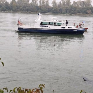 Die Wasserschutzpolizei begleitet von einem Schiff aus die Bergung des Autos im Rhein.