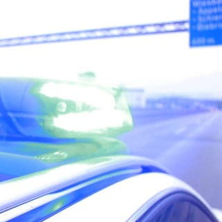 Ein Polizeiauto der Mainzer Polizei mit Blaulicht auf der Autobahn.