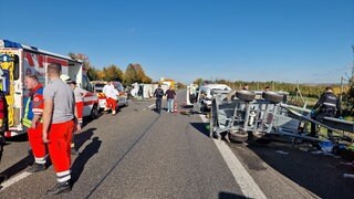 Nach dem Unfall auf der A63 bei Saulheim liegen die beschädigten Fahrzeuge auf der Fahrbahn. Rettungskräfte und Polizei sind im Einsatz.