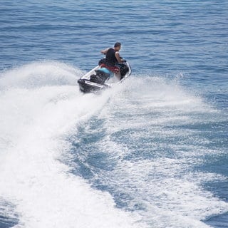 Ein Mann auf einem Jetski in voller Fahrt.