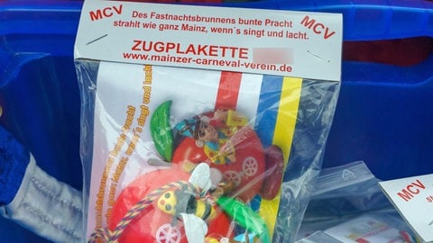 Eine Zugplakette für den Mainzer Rosenmontagszug liegt in einer Tüte und wird am Straßenrand verkauft. Der Erlös der Plakettchen fließt in die Finanzierung des Rosenmontzagszugs in  Mainz. 