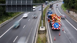 Bauarbeiter mit Fahrzeug stehen auf einen gesperrten Fahrbahn: Auf der A66 bei Wiesbaden wird saniert, deswegen kommt es am Schiersteiner Kreuz zu Behinderungen. 