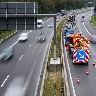 Bauarbeiter mit Fahrzeug stehen auf einen gesperrten Fahrbahn: Auf der A66 bei Wiesbaden wird saniert, deswegen kommt es am Schiersteiner Kreuz zu Behinderungen. 