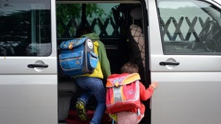 Kinder steigen in ein Auto.