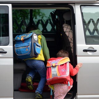 Kinder steigen in ein Auto.