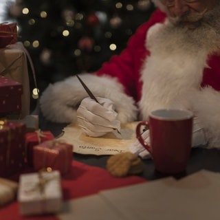 Ein Weihnachtsmann schreibt einen Brief. 