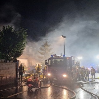 Feuerwehrleute löschen den Brand eines Hauses in Gau-Odernheim, das nach einem Sauna-Brand Feuer gefangen hatte.