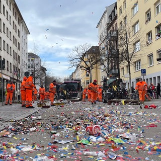 Beschäftigte des Abfallwirtschaftsbetriebs in mainz kehren die Boppstraße, nachdem der Rosenmontagszug dort durchgezogen ist.