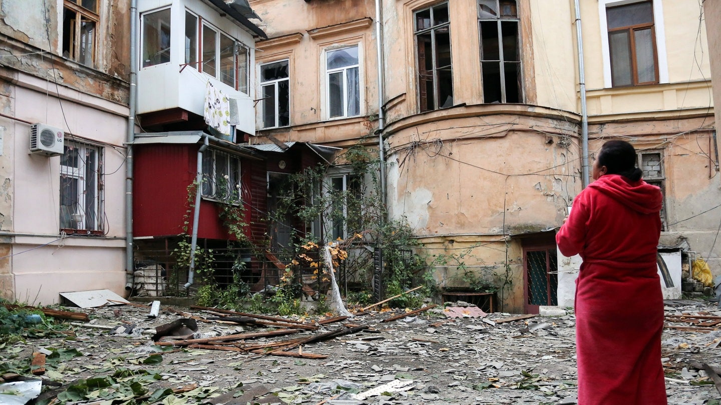 Nach einem russischen Luftangriff Mitte November in Odessa steht eine Frau in einem Bademantel vor stark zerstörten Wohnhäusern.