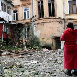 Nach einem russischen Luftangriff Mitte November in Odessa steht eine Frau in einem Bademantel vor stark zerstörten Wohnhäusern. 