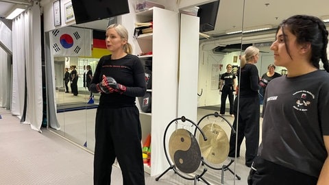 Mehrere Frauen in einem Trainingsraum üben die Selbstverteidigung.