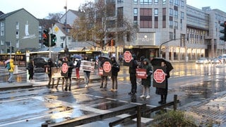 Mit Banner und Plakaten kritisieren Protestierende die Fleischindustrie. 