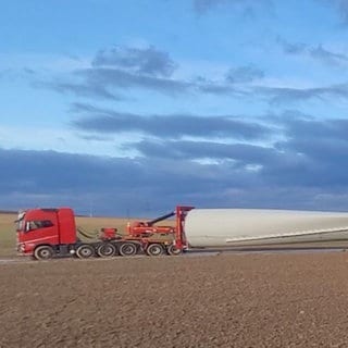 Ein Schwertransporter liefert das gigantische Rotorblatt eines Windrades in den Windpark Gau-Bickelheim.