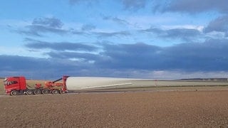 Ein Schwertransporter liefert das gigantische Rotorblatt eines Windrades in den Windpark Gau-Bickelheim.