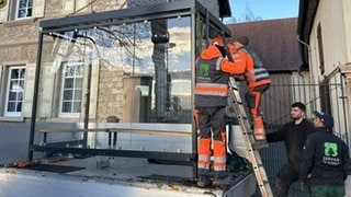 Mitarbeiter der Firma Serhan helfen beim Transport des Buswartehäuschens von Monzernheim nach Hangen-Weisheim.