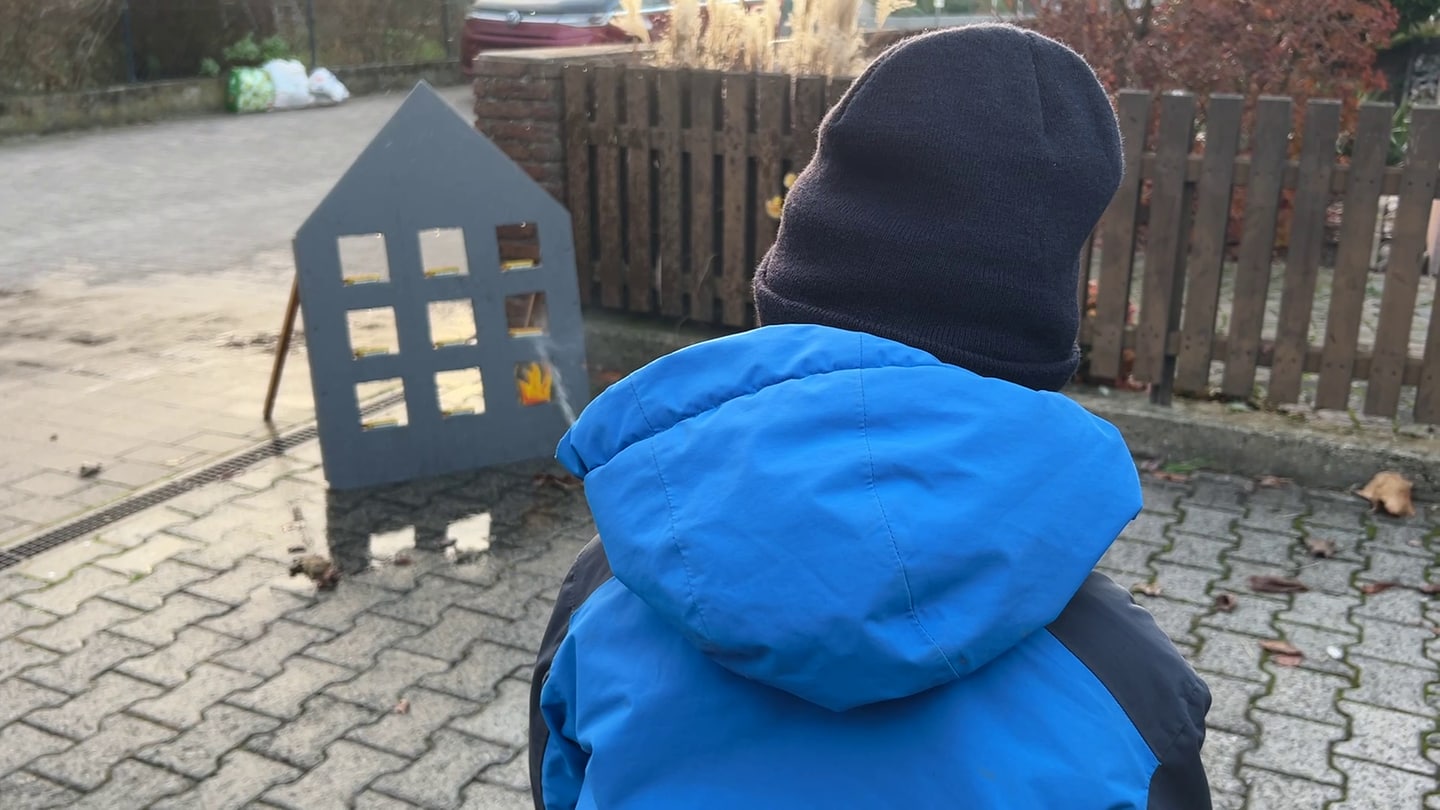 Ein Junge zielt bei der Bambini-Feuerwehr mit einem Wasserstrahl auf eine Flamme aus Papier. Mit dem Angebot wollen Feuerwehren Kinder früh für ein Engagement begeistern.