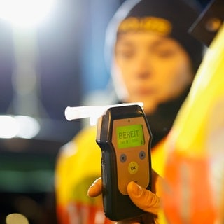 Eine Polizistin hält einen Alkoholtester in der Hand.