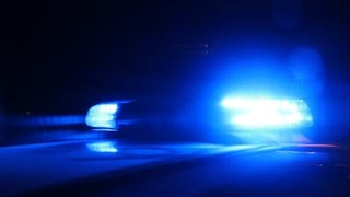 Ein Polizeiauto fährt mit Blaulicht durch die Nacht.