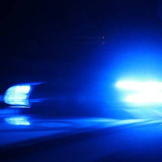 Ein Polizeiauto fährt mit Blaulicht durch die Nacht.