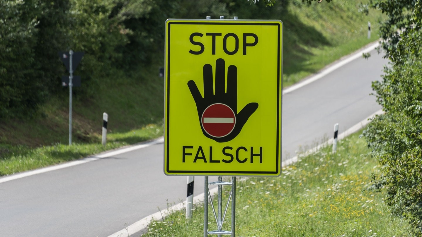 Ein grellgelbes Schild warnt vor dem falschen Einfahren auf eine Autobahn.