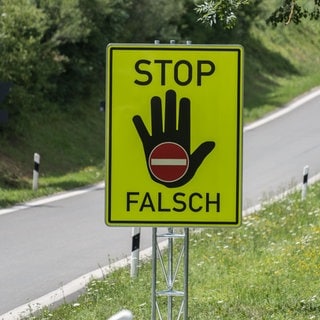 Ein grellgelbes Schild warnt vor dem falschen Einfahren auf eine Autobahn.